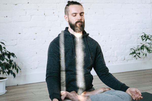 ragazzo seduto in meditazione con raggio di lice che gli passa sul viso e la pancia a simbolo della respirazione per ansia